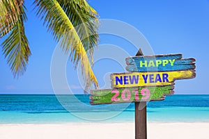 Hapy new year 2019 on a colored wood direction signs, beach and palm tree background