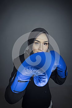 Hapyy face young businesswoman in suit with boxing glove