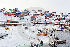 Harbor area with motorboats and colorful inuit houses in backgroung, Aasiaat city