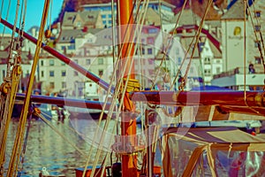 Harbor of the city of Alesund with tour boat and old sail boat, with buildings in the background