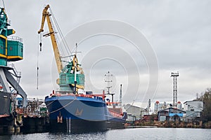 Harbor cranes and moored ship in port