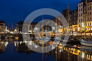 Harbor Honfleur at night with ships and restaurants, France