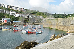Harbour of small Cornish fishing village with houses in background