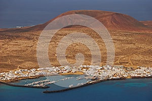 Harbour & town of Caleta de Sebo with volcanic mountain background, the main settlement with white houses on La Graciosa, Spain