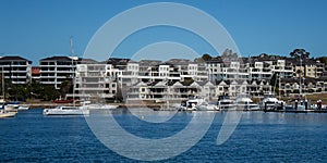 Harbourside condominium apartment housing with boats floating on blue water against blue sky