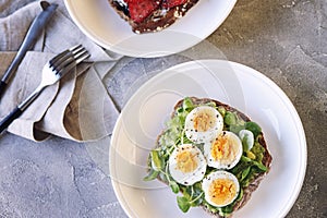 Hard boiled egg on avocado toast with green leaves and toast with fresh strawberries and cream cheese, healthy breakfast or lunch,