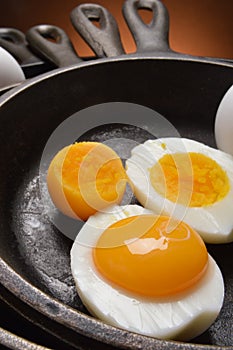 Hard boiled egg with fresh yoke in one half, all in cast iron skillets