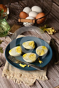 Hard boiled eggs on blue plate with ingredients around