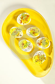 Hard boiled eggs, sliced in halves served on yellow plate