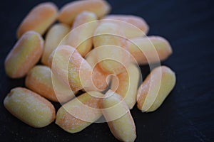 Close up food photography of candy sweets in orange and yellow colors and flavored with banana and mango on dark slate background