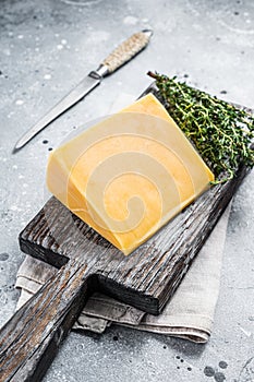 Hard cheese with knive on wooden cutting board. Parmesan. Gray background. Top view