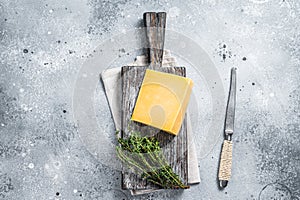 Hard cheese with knive on wooden cutting board. Parmesan. Gray background. Top view