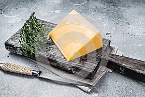 Hard cheese with knive on wooden cutting board. Parmesan. Gray background. Top view