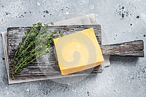 Hard cheese with knive on wooden cutting board. Parmesan. Gray background. Top view