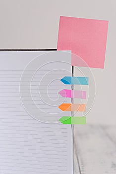 Upper view striped lined hard cover note book blank color sticky note arrow banners inserted clear background. Reminder