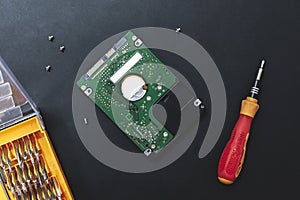 Hard disk drive and set of screwdriver at black background. repair hdd after diagnostics. data maintenance after virus attack