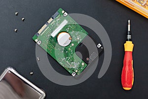 Hard disk drive and set of screwdriver at black background. repair hdd after diagnostics. data maintenance after virus attack