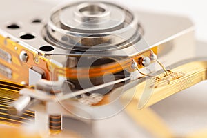 Hard drive detail with shiny metal and golden color parts on light background macro