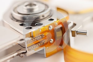 Hard drive detail with shiny metal parts and orange tape on light background macro