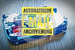 Hard drive 3.5 inches as a data storage with motherboard on a bamboo table and in german Automatische E-Mail-Archivierung in engli