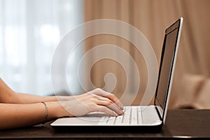 The hard hands of a businessman are typing on a laptop keyboard against the background of a blurred room. Concept for workplace,