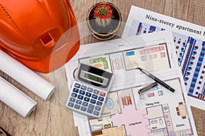 Hard hat with blueprints and rulers, pen, calculator on desk