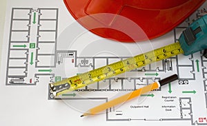 Hard hat, yellow pencil, measuring tape and building plans