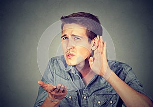 Hard of hearing man placing hand on ear asking someone to speak up