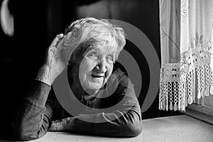 A hard-of-hearing old woman puts her hand to her ear. Black and white photo.