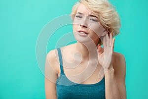 A hard-of-hearing young beautiful woman putting her hand to her ear