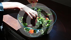 hard light female hands making greek green salad, stirring with forks, closeup salad bowl