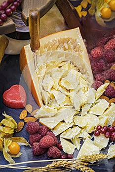 Hard organic mature cheese, cheese knife, rough pieces, assorted with fruits, nuts, top view. Healthy eating