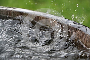 Hard rain is falling in a wooden barrel full of water in the garden