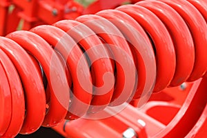 Hard red spring made of steel. Part of big industrial or agricultural machine