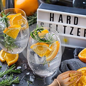 Hard seltzer cocktail with orange, rosemary and bartenders accessories
