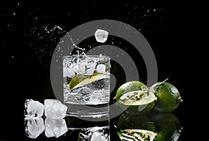 hard seltzer with lime on a dark wooden background, ice cubes fall into a glass with an alcoholic beverage hard seltzer