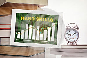 Hard skills and financial growth graph trading on digital computer tablet with stack of textbook