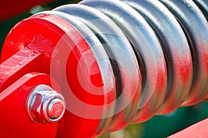 Hard spring made of steel. Part and detail of red industrial or agricultural machine