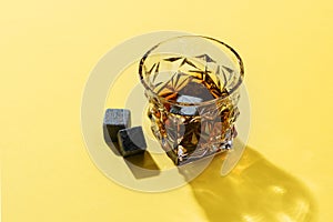 Hard strong alcoholic drinks in glass: cognac, tequila, scotch, brandy or whiskey on a yellow background