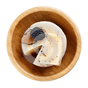 Hard truffle cheese and black truffles in wooden bowl isolated on white