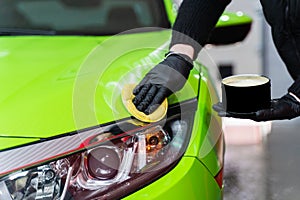 Hard wax for protection paintwork of car using sponge for remove paint scratches. Applying hard wax with a yellow sponge photo