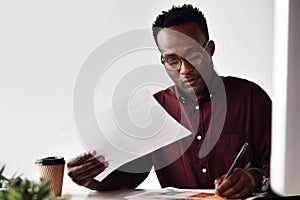 Hard work does not frighten me. a handsome young businessman sitting and making notes while working with documents in