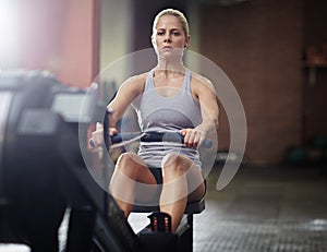 This hard work is going to pay off. a young woman working out on a rowing machine in a gym.