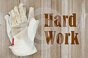 Hard Work message with dirt covered leather work gloves on wood