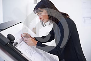 Hard at work on a new design. a female architect working on a building plan at a drawing board.