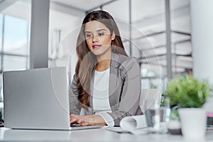 Hard work is no stranger to her. a young businesswoman working on a laptop in an office.