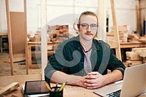 Hard work is what turns your business into a success. Portrait of a handsome young carpenter working on a laptop inside