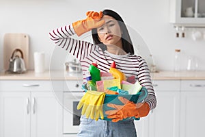 Hard-working asian woman with busket full of cleaning supplies