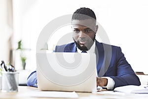 Hard-working black man typing on laptop in office