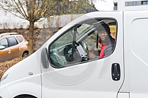 Hard-working focused Black delivery man checking the address and crossing it off of digital lis placed on his laptop